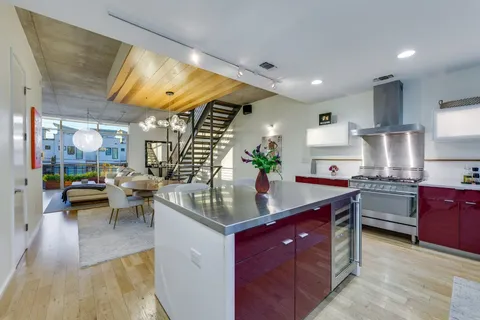 a kitchen with stainless steel appliances granite countertop a sink a stove and a wooden floors