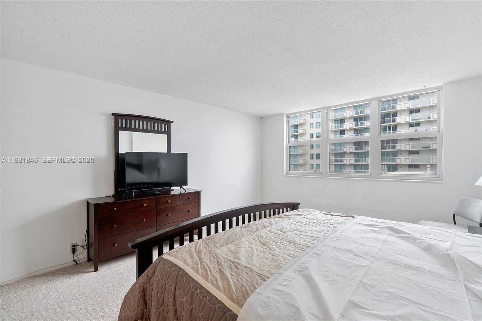 9511 Collins Avenue, Unit 606 Surfside, FL 33154 - Photo 17 of 43 a bedroom with a bed and a flat screen tv
