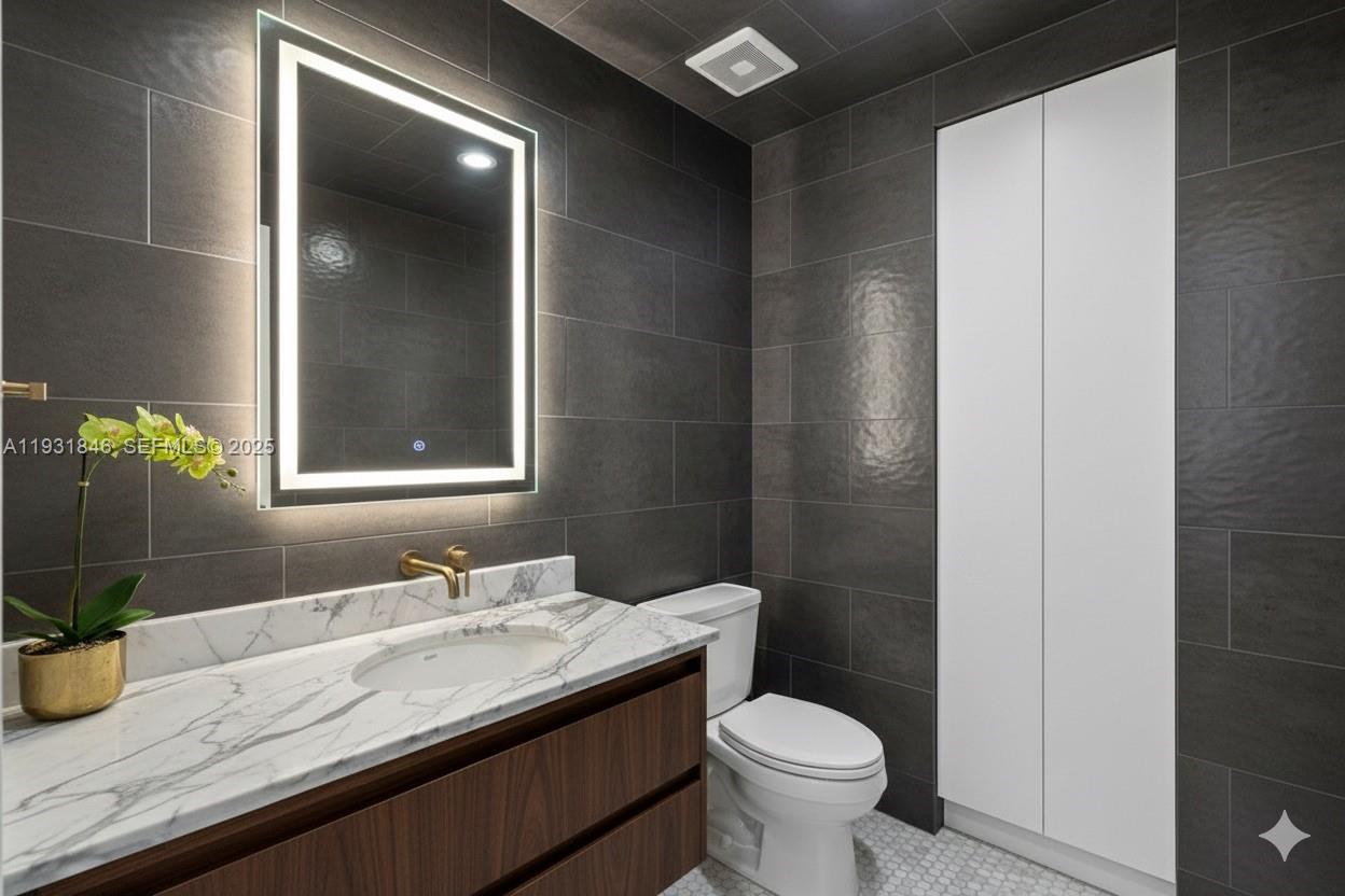 9511 Collins Avenue, Unit 606 Surfside, FL 33154 - Photo 24 of 43 a bathroom with a granite countertop sink a toilet and a mirror