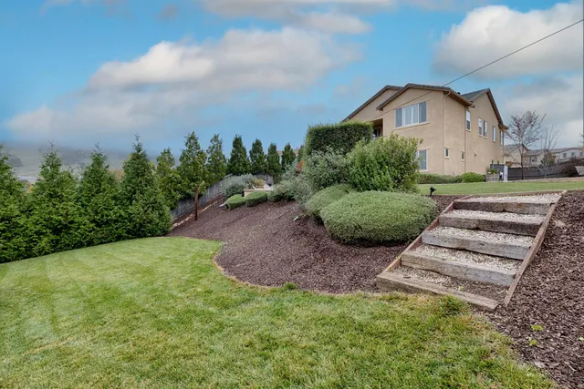 a view of a back yard with flower plants and wooden fence