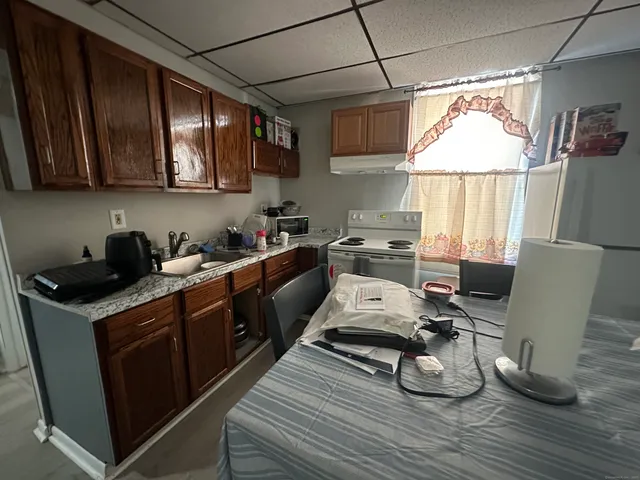 a kitchen with stainless steel appliances granite countertop a stove a sink dishwasher and white cabinets with wooden floor