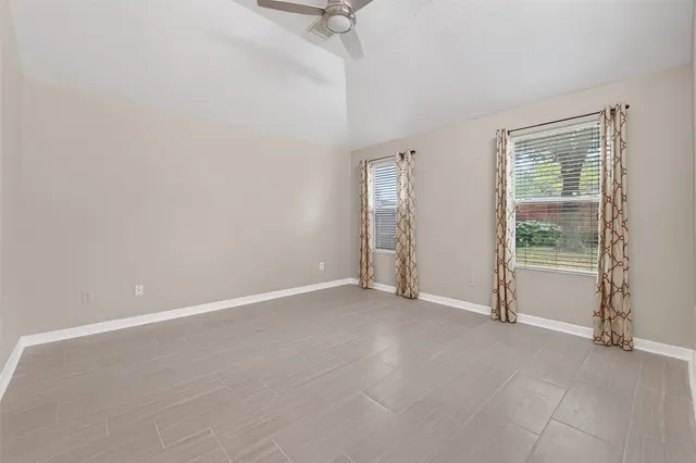 an empty room with a ceiling fan and windows