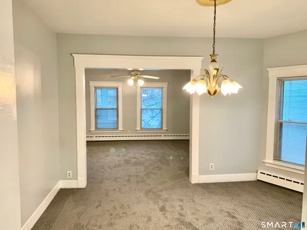 a view of a livingroom with a chandelier fan and windows