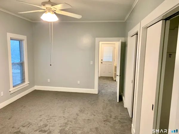 a view of a room with a ceiling fan and closet area