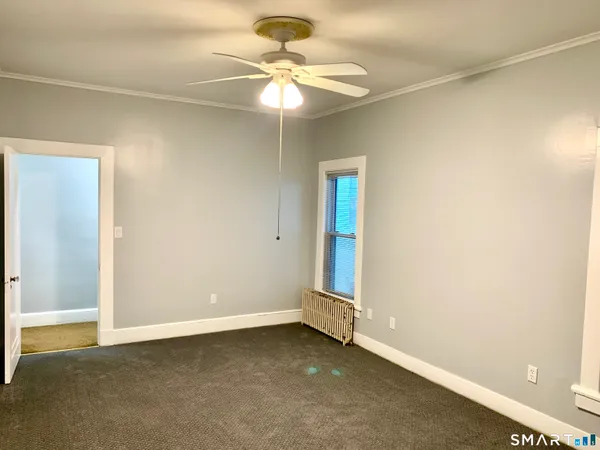 an empty room with a window and a fan