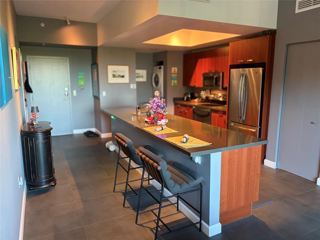 2301 Wilton Drive, Unit R309 Wilton Manors, FL 33305 - Photo 9 of 26 a kitchen with stainless steel appliances kitchen island granite countertop dining table chairs and a refrigerator