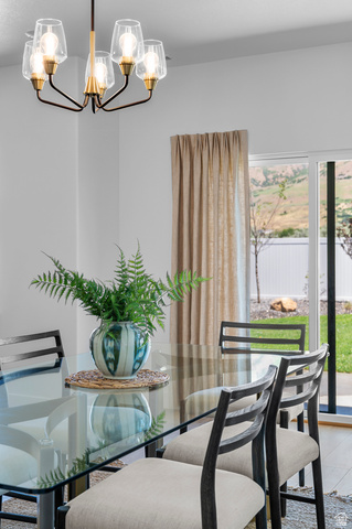 1352 West 2350 South, Unit 18 Perry, UT 84302 - Photo 22 of 26 Dining area featuring a contemporary chandelier with clear glass shades and a glass-top table