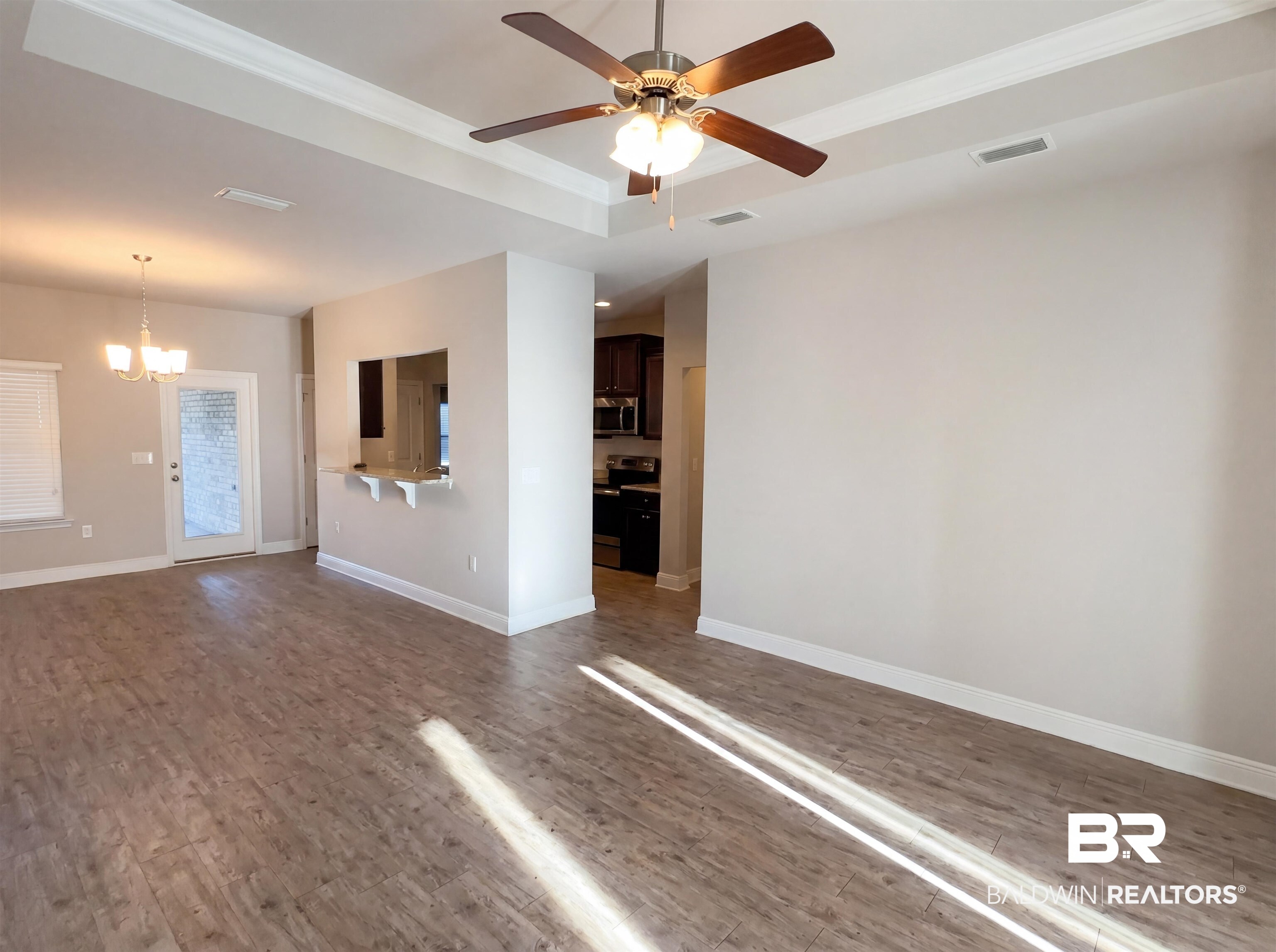 1740 Covington Lane Foley, AL 36535 - Photo 7 of 18 Open-concept living space featuring wood-finish flooring, a tray ceiling with a ceiling fan, and a pass-through window with a breakfast bar