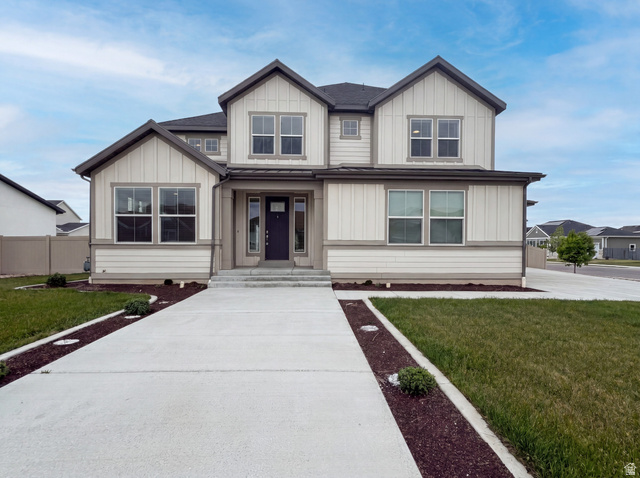 1251 North 2525 West Clinton, UT 84015 - Photo 1 of 30 Contemporary two-story residence featuring a dark gray roof, light siding with vertical board and batten accents, a dark entry door, and multiple large windows