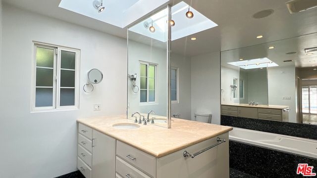 a bathroom with a sink double vanity granite tub shower and a mirror