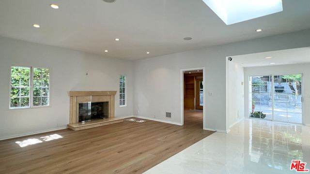 a view of an empty room with window and wooden floor