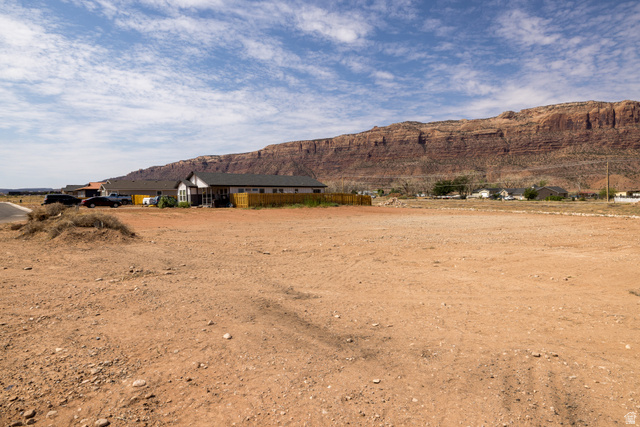 88 Lidia, Unit 22 Moab, UT 84532 - Photo 9 of 18 Expansive undeveloped lot featuring rugged terrain, a backdrop of natural rock formations, and a distant residential setting