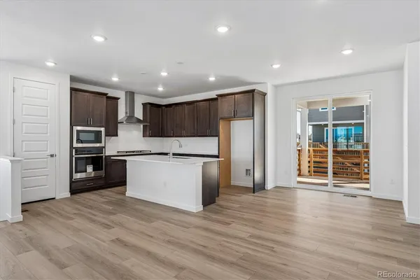 a large kitchen with a center island wooden floor stainless steel appliances and cabinets