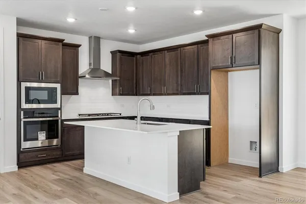 a kitchen with a refrigerator a stove top oven and cabinets
