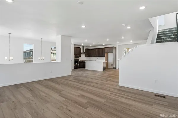 a view of kitchen with kitchen island a sink wooden floor and a refrigerator