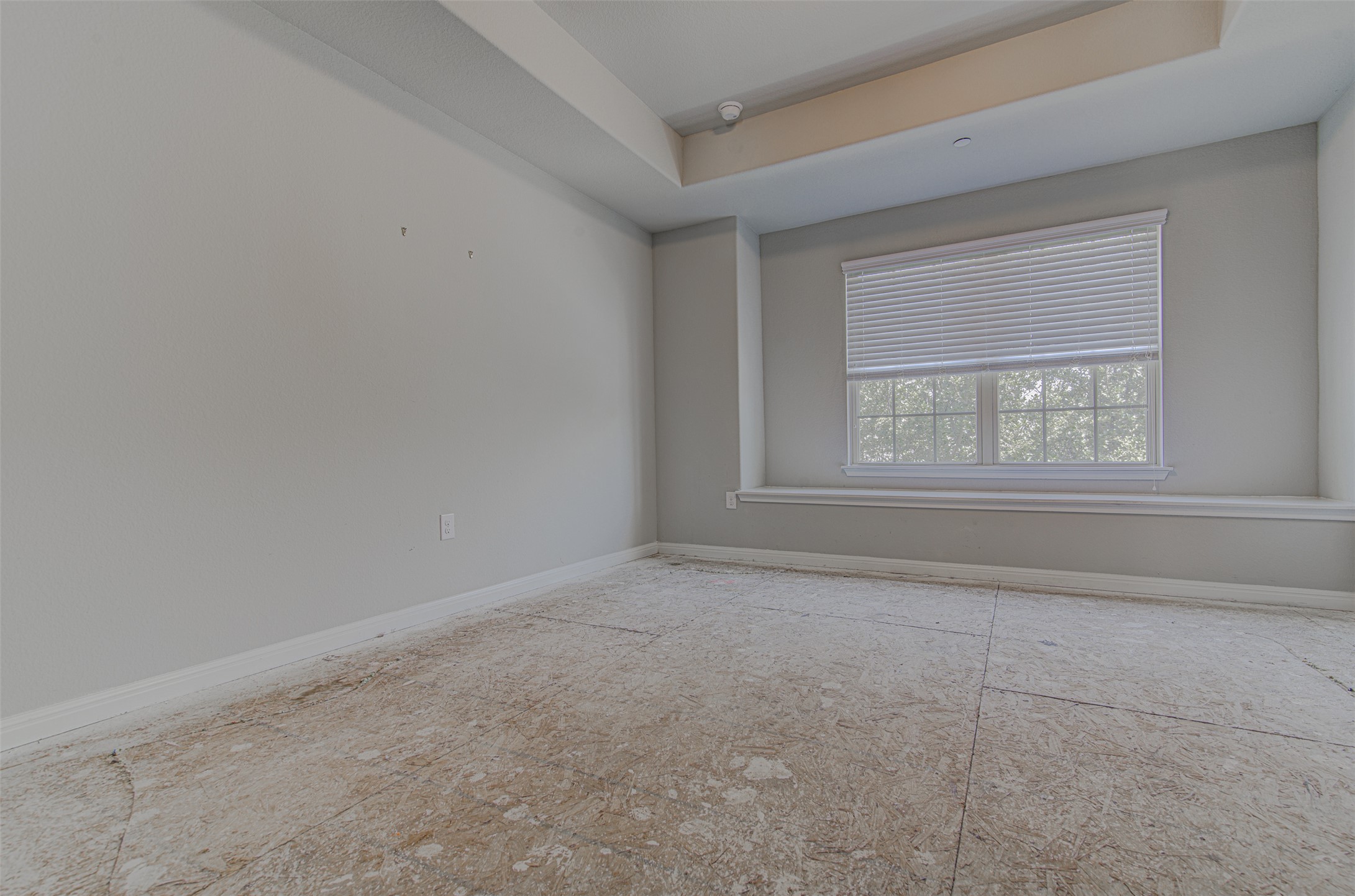 1407 Airedale Road, Unit 1104 Austin, TX 78748 - Photo 18 of 26 A well-lit bedroom awaits new flooring, featuring a large window with blinds and a tray ceiling.