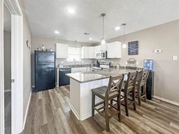 a kitchen with stainless steel appliances a dining table chairs stove refrigerator and cabinets