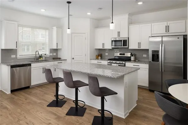 a kitchen with stainless steel appliances a stove a sink a oven a refrigerator a dining table and chairs