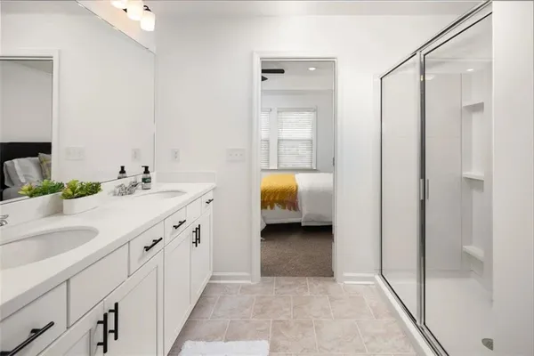 a en suite bathroom with a double vanity sink a mirror and a shower