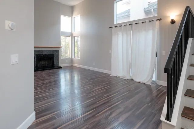 an empty room with wooden floor fireplace and windows