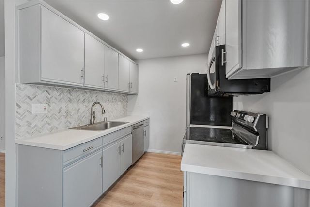 a kitchen with stainless steel appliances granite countertop a sink stove and refrigerator