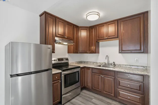 a view of kitchen and empty room with wooden floor