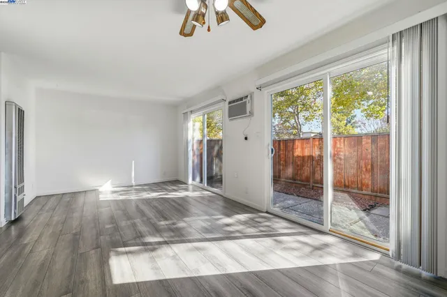 an empty room with wooden floor fan and windows
