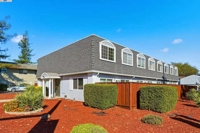 a view of empty room with wooden floor and kitchen