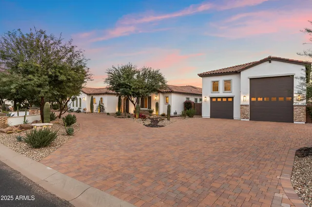 a view of a white house with a large tree and couches