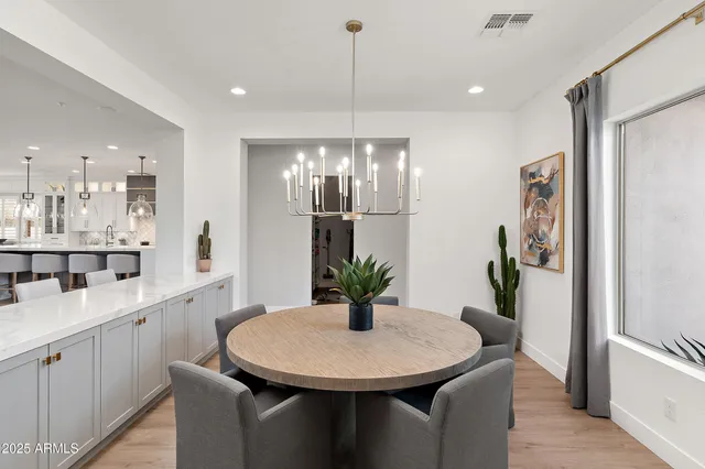a dining hall with stainless steel appliances kitchen island a table chairs and chandelier