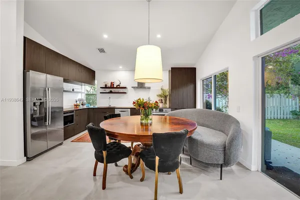 a dining room with furniture a chandelier and kitchen view