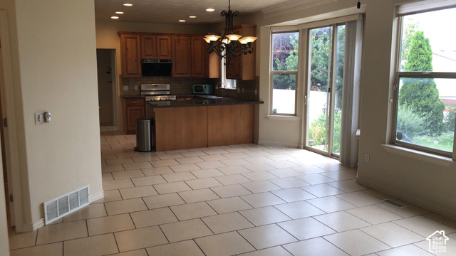 Open-concept kitchen featuring wood cabinetry, stainless steel appliances, and a central island with a breakfast bar