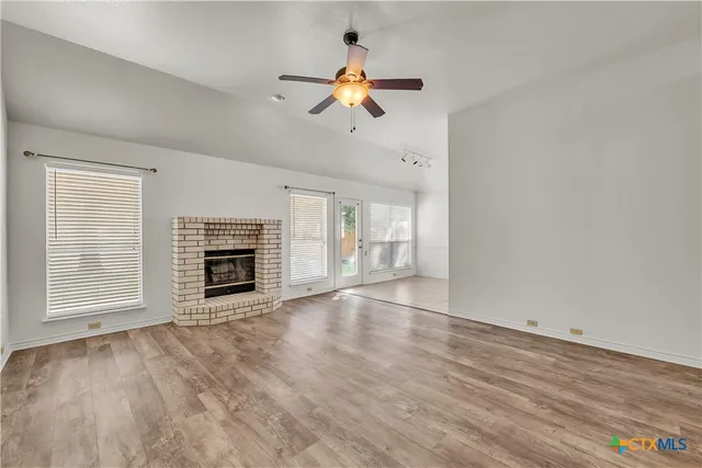 a view of an empty room with a fireplace and a window