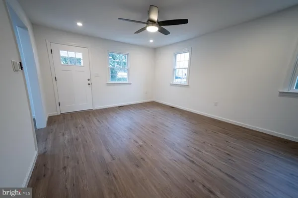 a view of an empty room with a window and wooden floor