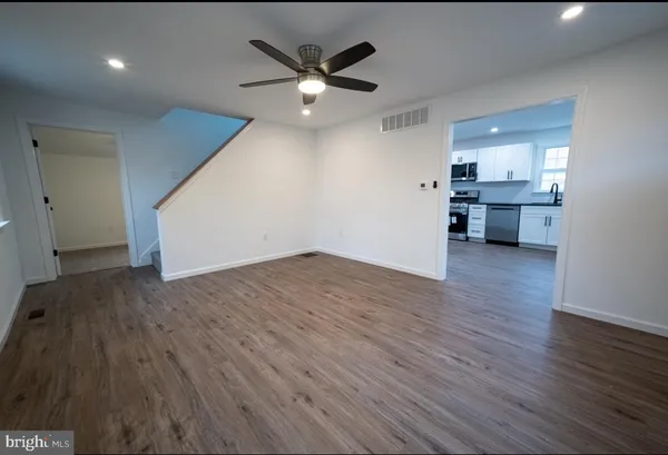 a view of empty room with wooden floor and ceiling fan