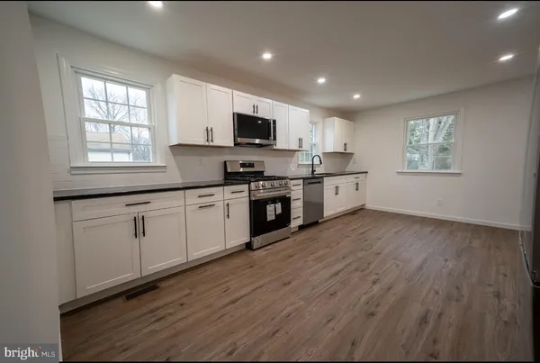 a large kitchen with stainless steel appliances granite countertop a stove a sink dishwasher and a microwave with wooden floor