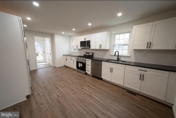 a kitchen with stainless steel appliances granite countertop a sink a stove and cabinets