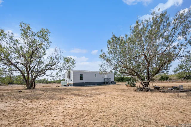 a view of a white house with a large tree