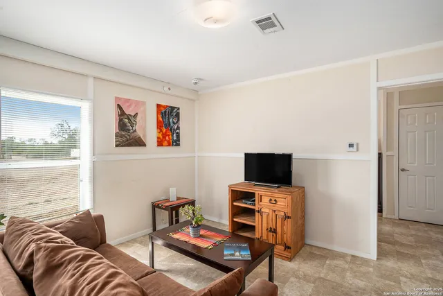 a living room with furniture a flat screen tv and a window