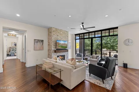 a living room with furniture large windows and wooden floor