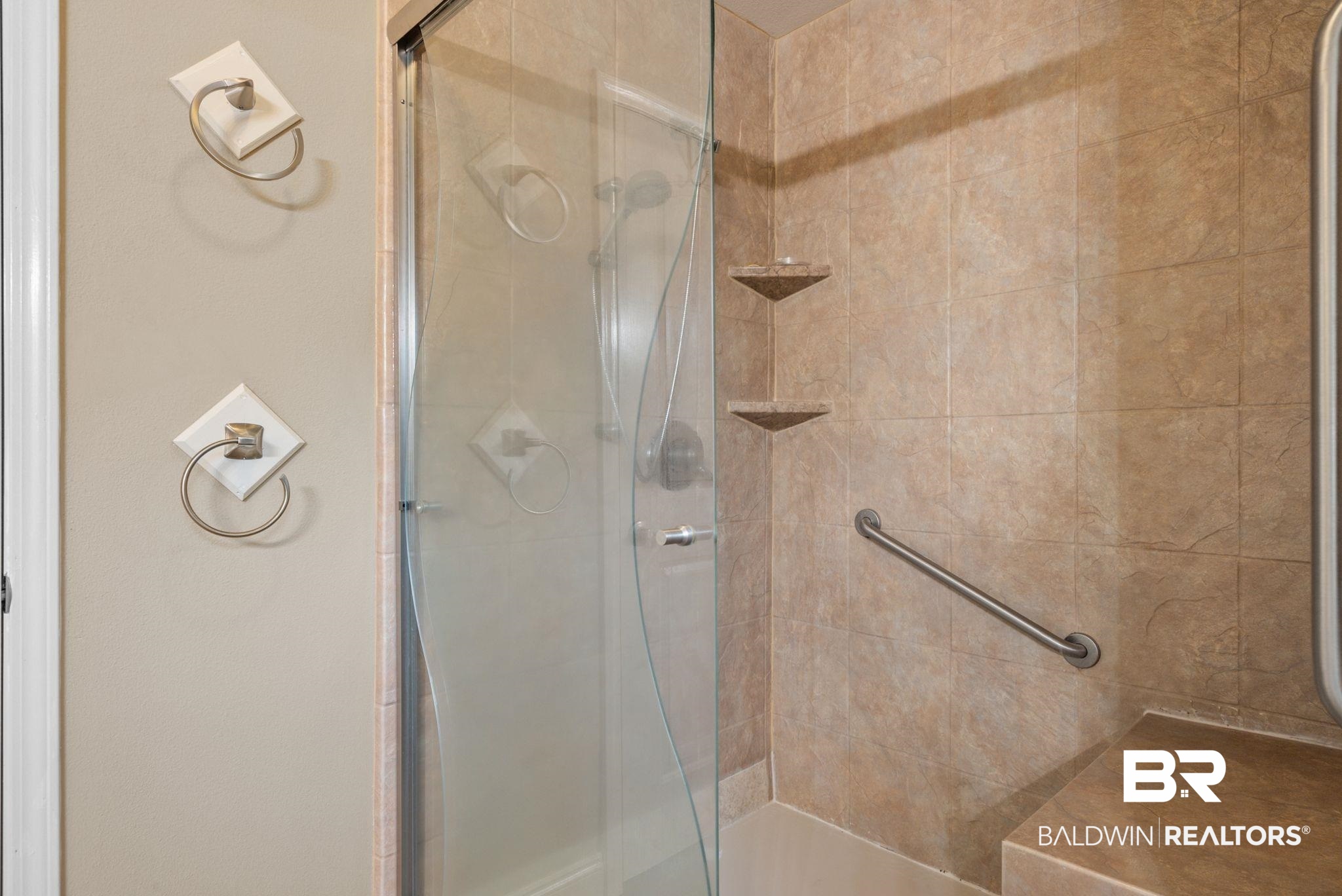 562 Vestige Mews Foley, AL 36535 - Photo 34 of 54 Tiled shower enclosure featuring a clear glass door, two built-in corner shelves, a grab bar, and a built-in shower bench