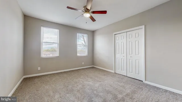 an empty room with windows and fan