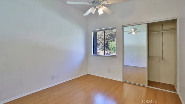 an empty room with wooden floor closet and windows