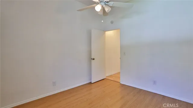 an empty room with a chandelier fan and wooden floor