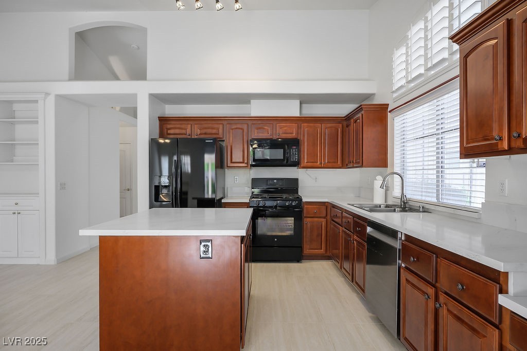 1812 Jack Rabbit Way Las Vegas, NV 89128 - Photo 14 of 44 Kitchen featuring black appliances, a center island, and brown cabinetry