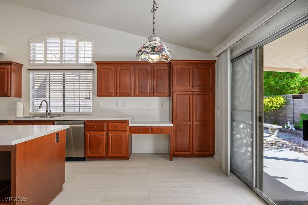 1812 Jack Rabbit Way Las Vegas, NV 89128 - Photo 15 of 44 Kitchen with vaulted ceiling, dishwasher, light tile patterned floors, brown cabinetry, and pendant lighting