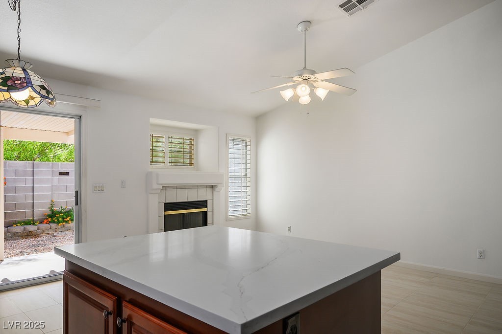 1812 Jack Rabbit Way Las Vegas, NV 89128 - Photo 17 of 44 Kitchen with a kitchen island, a tiled fireplace, pendant lighting, light countertops, and light tile patterned flooring