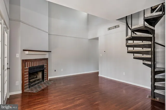 an empty room with wooden floor entryway and windows
