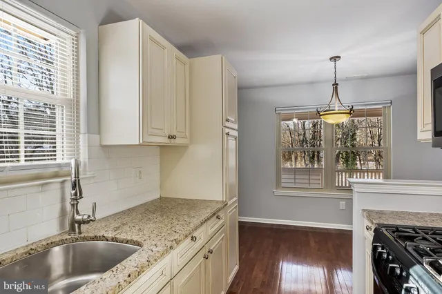 a kitchen with granite countertop a sink a counter space appliances and cabinets