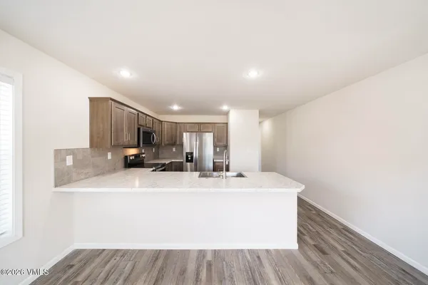 a large white kitchen with sink and a refrigerator